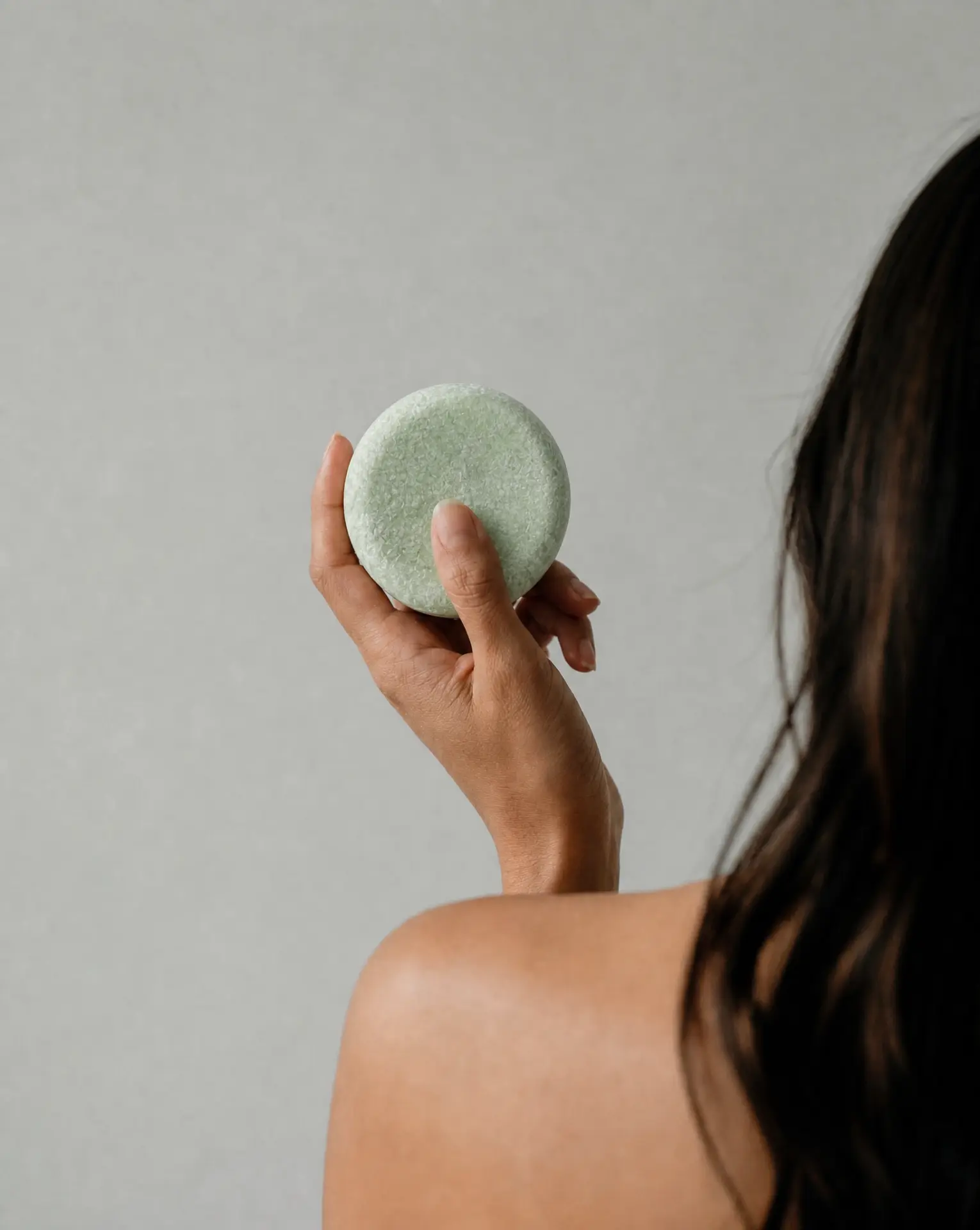 Woman holding a green solid shampoo bar